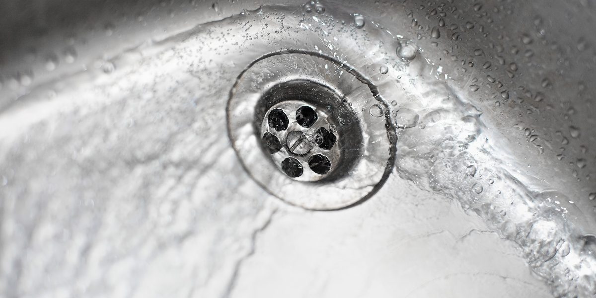 Bonde de lavabo vue de près, l'eau peine à s'écouler