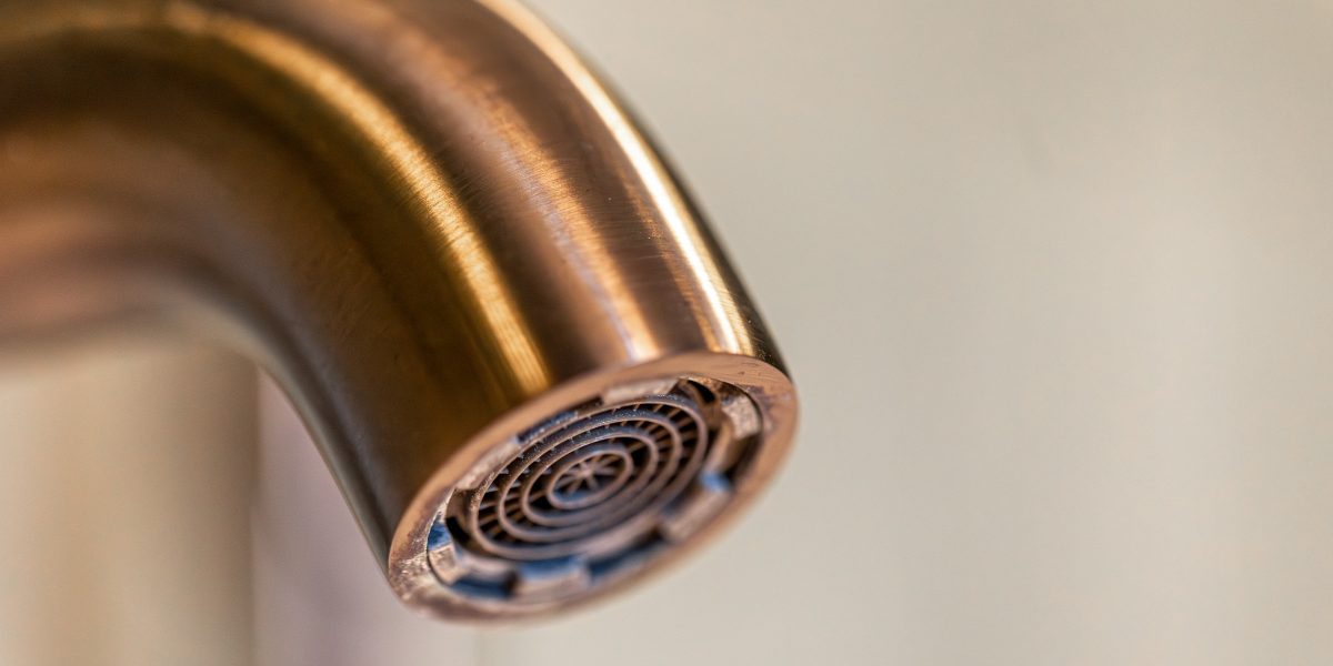 Gros plan sur le mousseur d'un robinet moderne, une goutte se forme