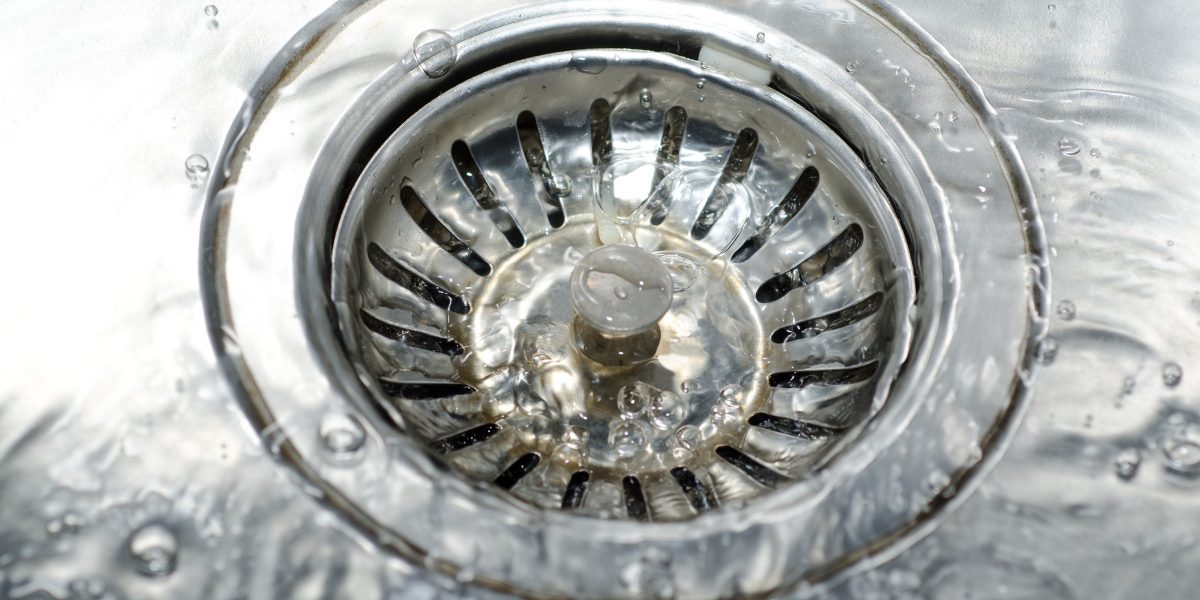 Bonde d'évier en inox vue de dessus, l'eau s'écoule autour de la grille