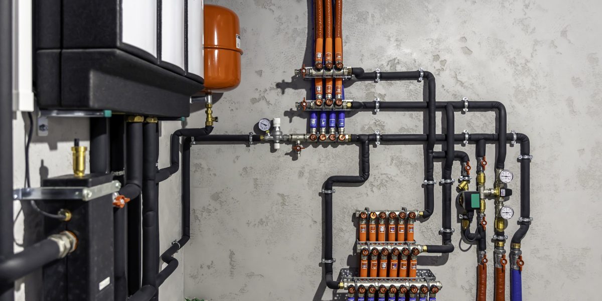 Local technique avec ballon d'eau chaude, vase d'expansion rouge et tuyauterie